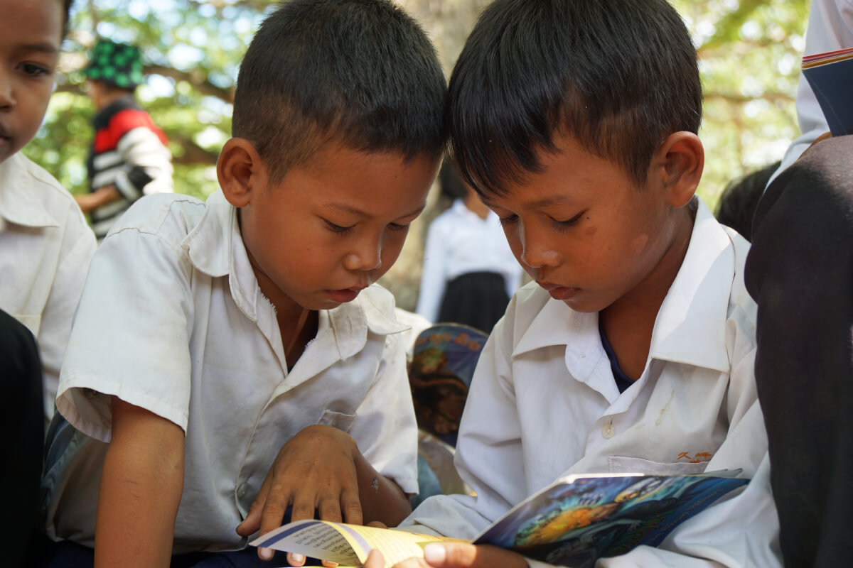 移動図書館の本を食い入るように読むカンボジアの子どもたち